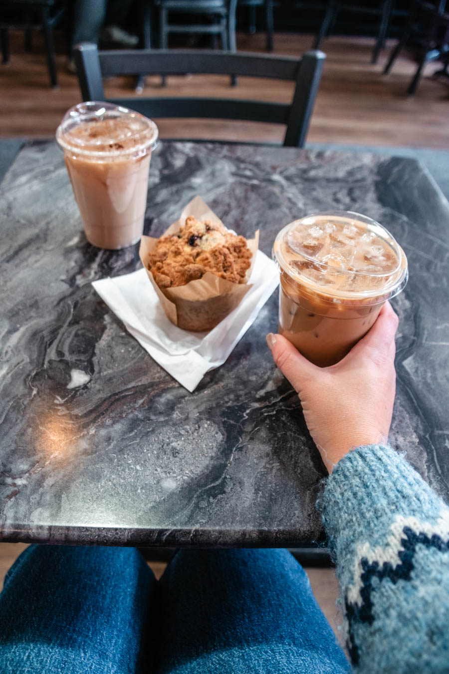 Image of two iced coffees and a muffin on a marble table – A delicious coffee break in Ithaca, featuring two iced lattes and a freshly baked muffin, enjoyed in a cozy café setting.