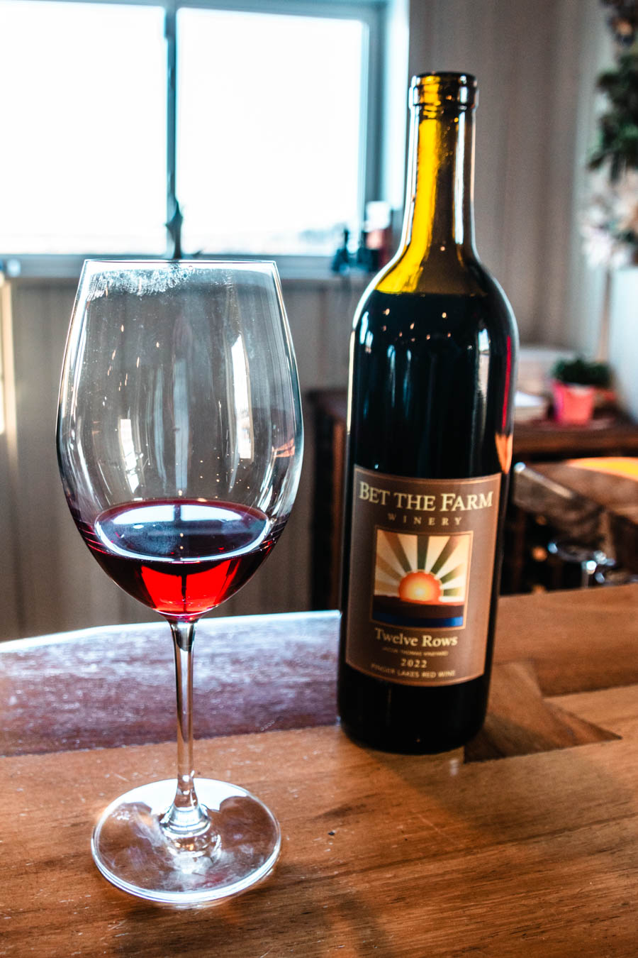 A bottle of ‘Bet the Farm Winery’ Twelve Rows red wine with a glass of wine, capturing the local wine culture.