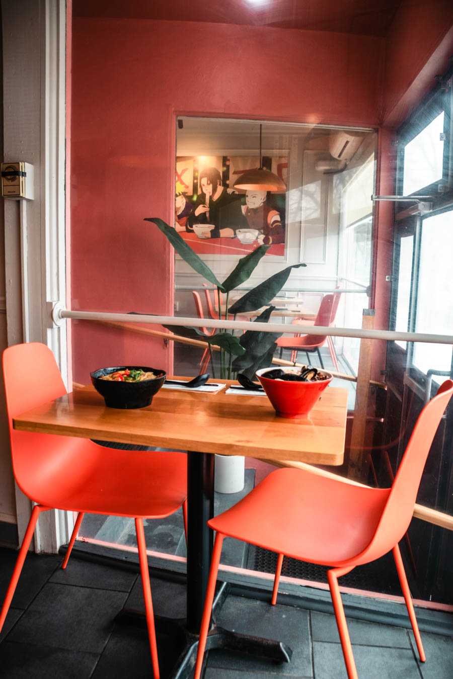 A cozy dining setup with ramen bowls on a wooden table, featuring stylish décor and warm hues.