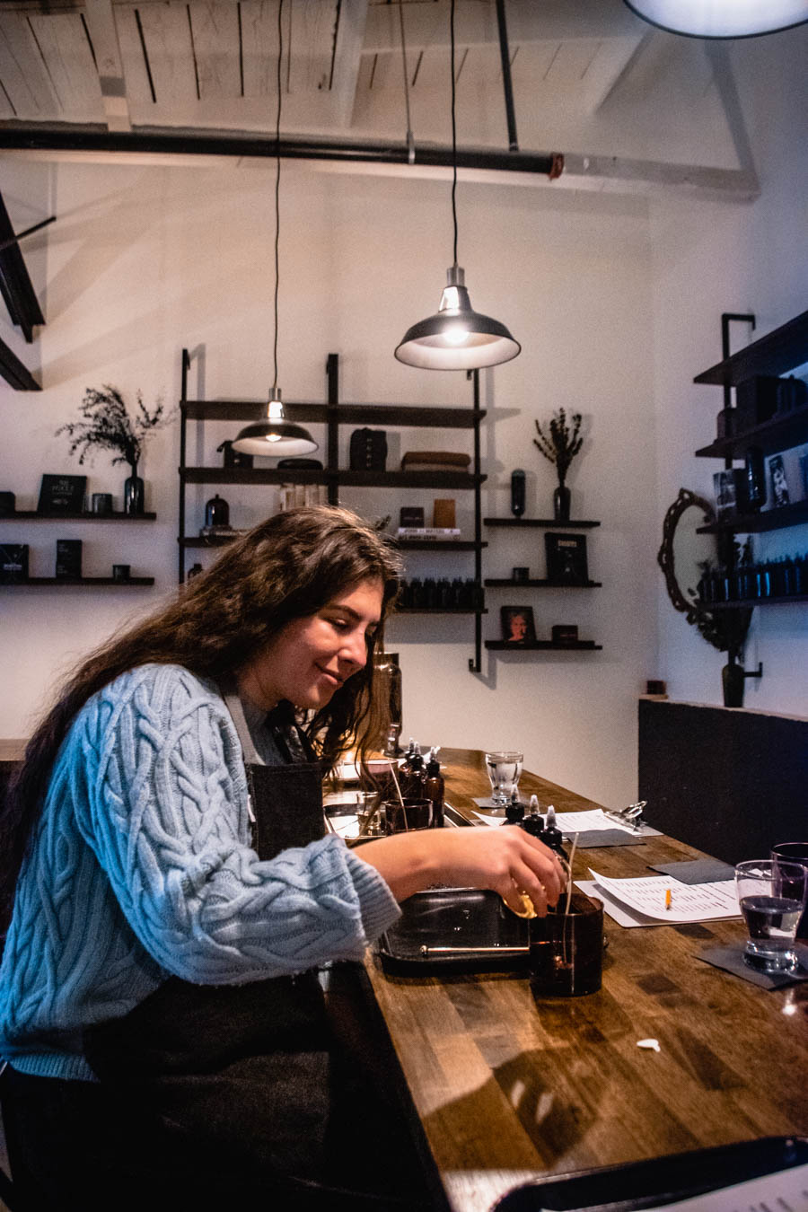 Traveler creating a custom fragrance at a candle-making studio, immersed in the hands-on experience.