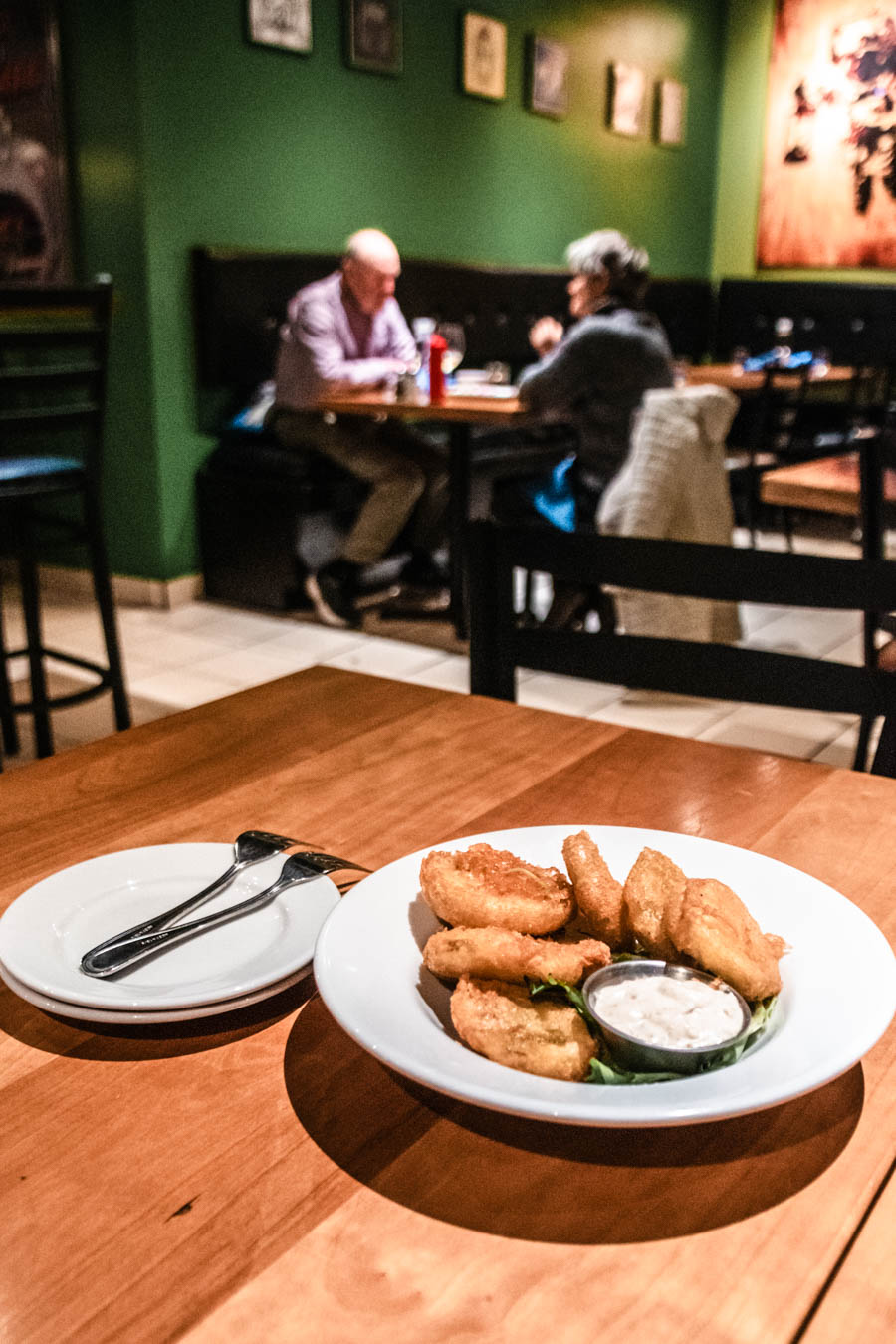 Classic pub dining experience – A plate of golden-fried appetizers with dipping sauce on a wooden table in a cozy restaurant.