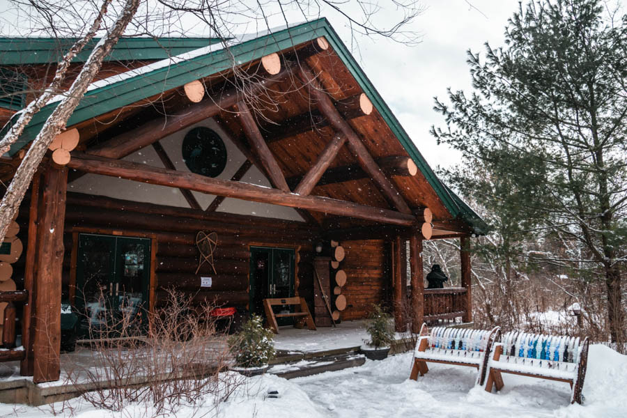 A rustic log cabin covered in snow, creating a perfect winter retreat surrounded by nature. - Lime Hollow Nature Center