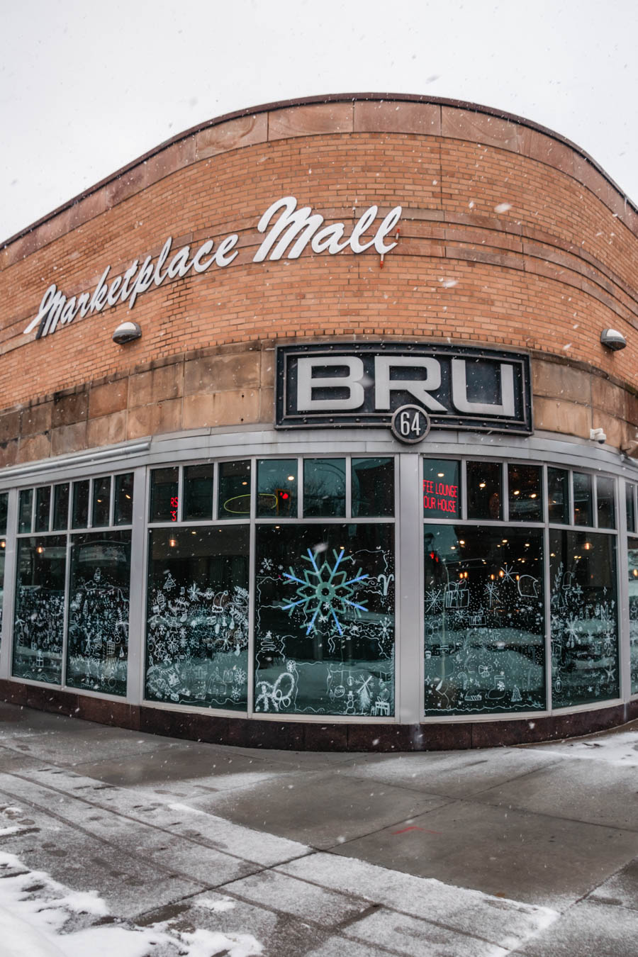 The exterior of BRU 64, a stylish café and tap room inside a historic brick building, with festive winter window decorations.