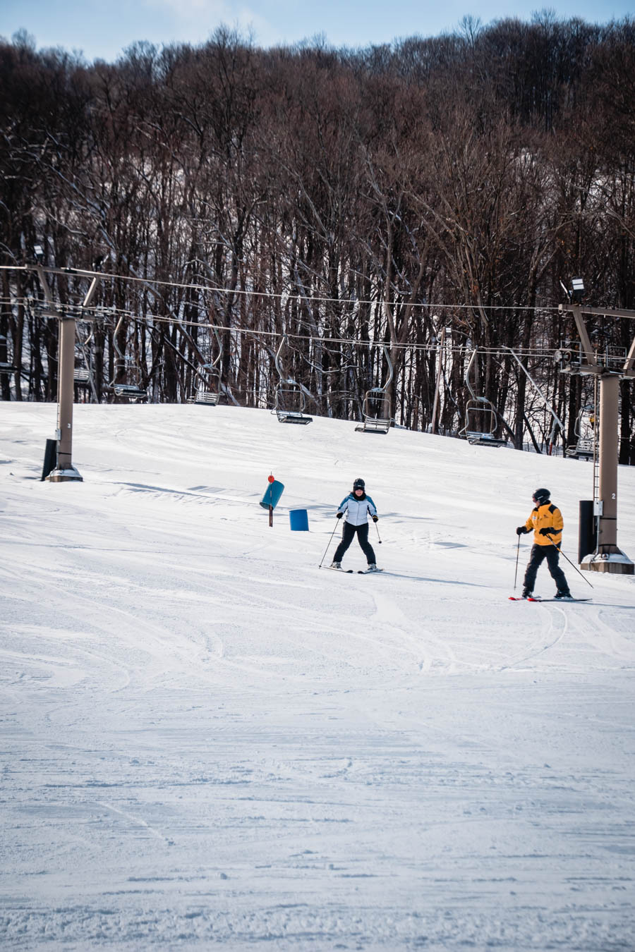 A woman learning to ski, surrounded by other skiers enjoying a bright, snowy day at a Finger Lakes ski resort.