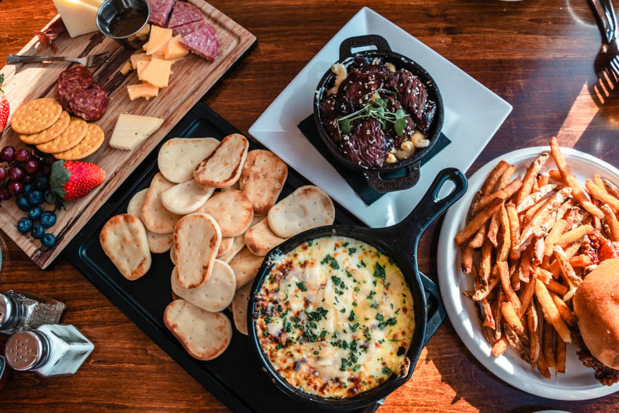 Delicious Winter Comfort Food – A table filled with warm, comforting dishes like cheesy dips, fries, and charcuterie, perfect for après-ski dining. 