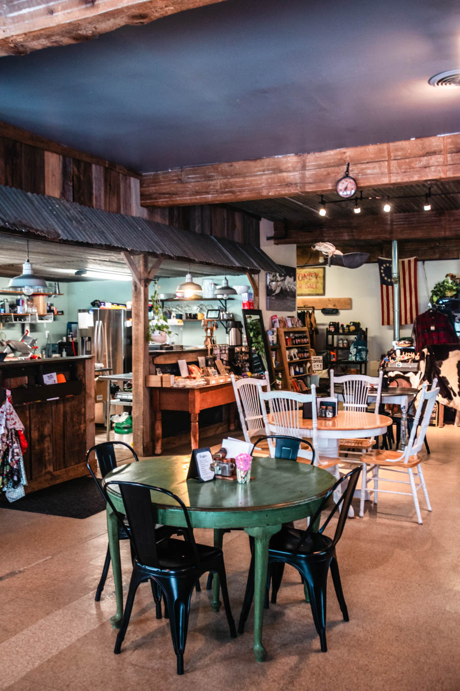 Cozy Café with Vintage Charm – The inviting interior of a small café, featuring rustic wooden beams, mismatched chairs, and local goods.